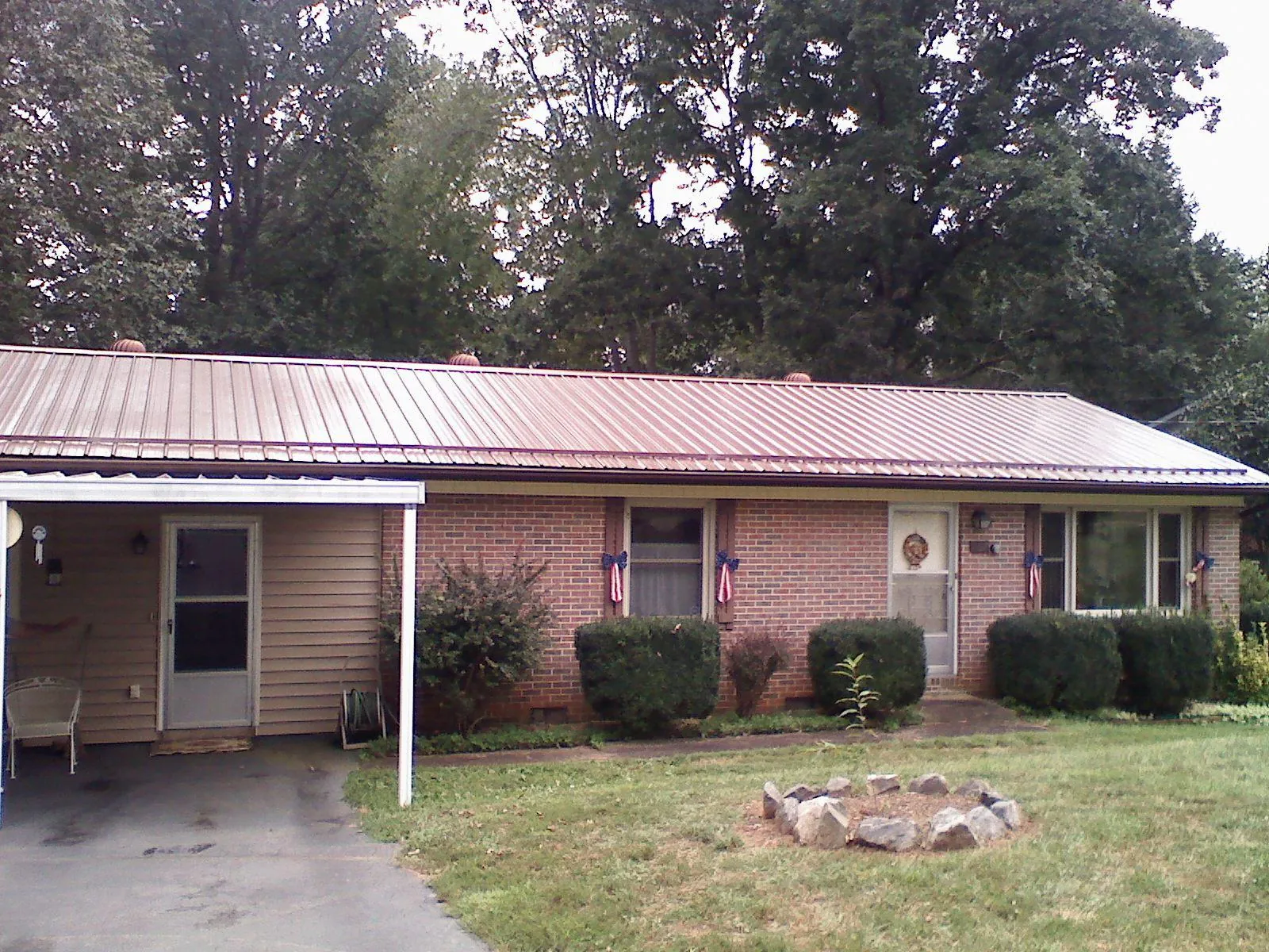 Bronze metal roof and carport on a brick ranch home — Roof Repair work by our crew in Lyons